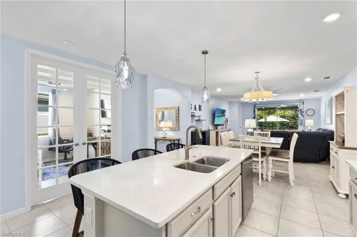 Kitchen featuring a kitchen island with sink, light stone counters, a breakfast bar, open floor plan, and light tile patterned floors