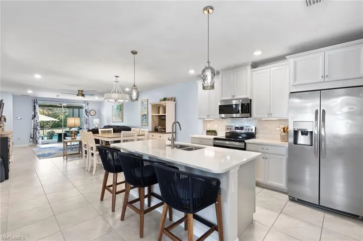 Kitchen with stainless steel appliances, open floor plan, a kitchen breakfast bar, light tile patterned floors, and hanging light fixtures
