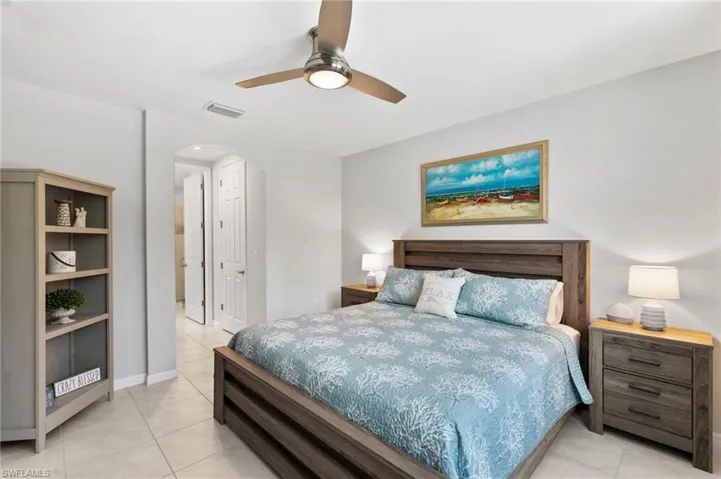 Bedroom featuring a ceiling fan, arched walkways, light tile patterned floors, and a closet