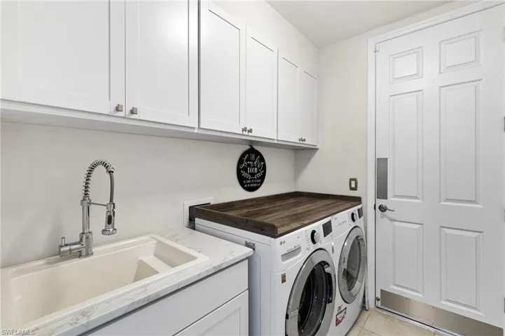 Laundry room featuring separate washer and dryer, light tile patterned floors, and cabinet space