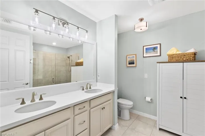 Bathroom featuring double vanity, a stall shower, and light tile patterned floors