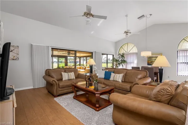Living area with lofted ceiling, hardwood / wood-style floors, and ceiling fan