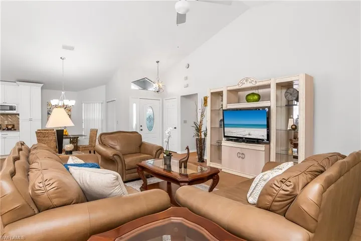Living area featuring a chandelier, vaulted ceiling, and a ceiling fan