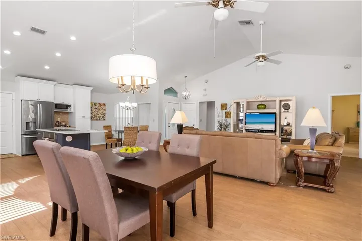 Dining area with light wood-style flooring, hanging lights, lofted ceiling, and a ceiling fan