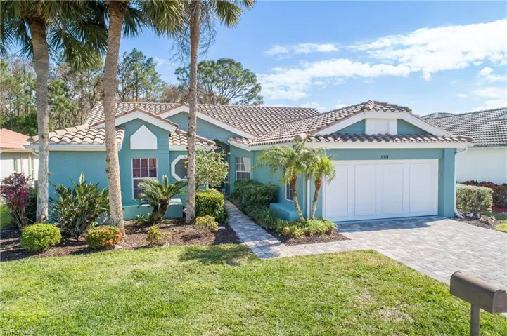 Mediterranean / spanish home with a tile roof, a front lawn, driveway, stucco siding, and an attached garage