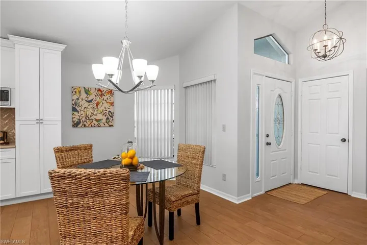 Dining room with a chandelier, light wood-type flooring, healthy amount of natural light, and lofted ceiling