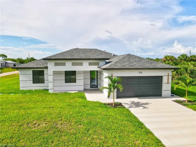View of front of property with a front yard, stucco siding, and driveway