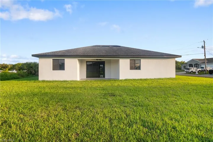 Back of property with stucco siding, a lawn, and a patio