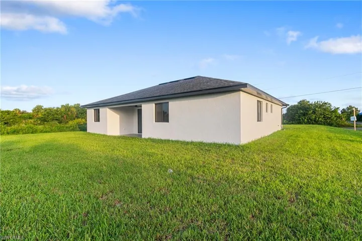 Back of house featuring a yard, stucco siding, and a patio area