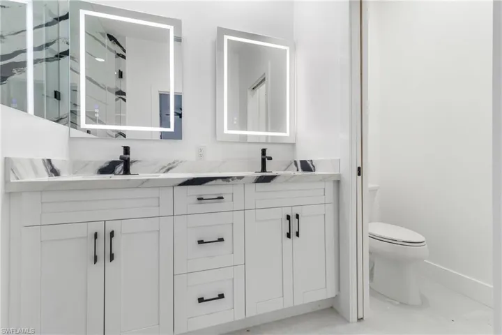 Bathroom with double vanity and a marble finish shower