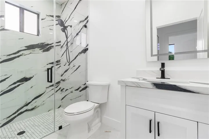 Bathroom with vanity and a marble finish shower