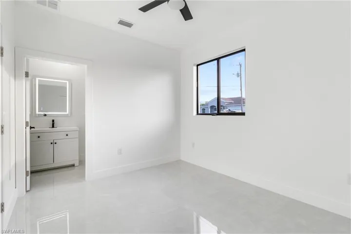 Unfurnished bedroom featuring a ceiling fan, ensuite bathroom, and finished concrete floors