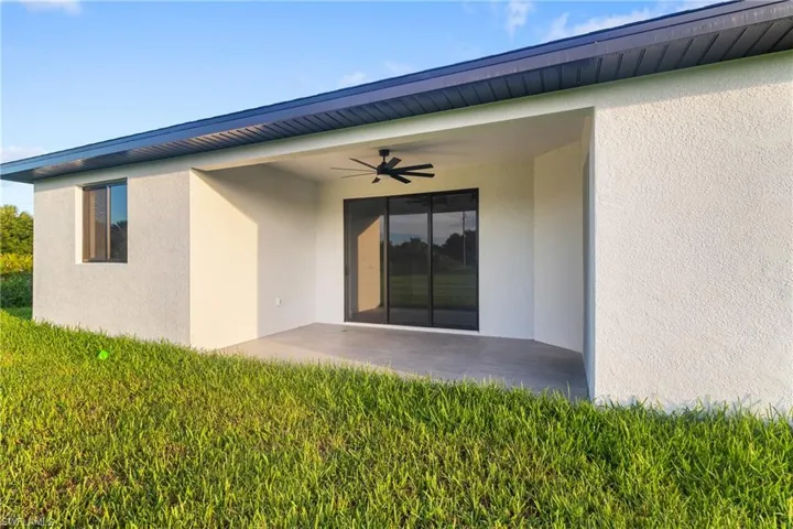 Rear view of house with a ceiling fan, a patio area, stucco siding, and a yard