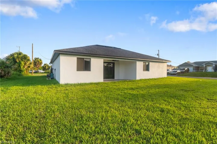 Rear view of property featuring a yard, stucco siding, and a patio