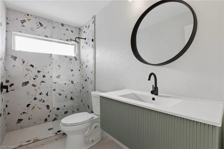 Contemporary bathroom featuring a walk-in shower with patterned wall tile and a linear window