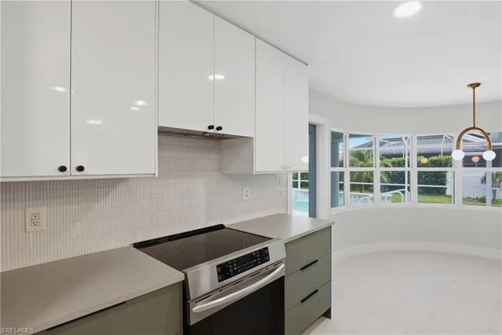 Modern kitchen featuring white flat-panel upper cabinetry, green flat-panel lower cabinetry, and a stainless steel electric range