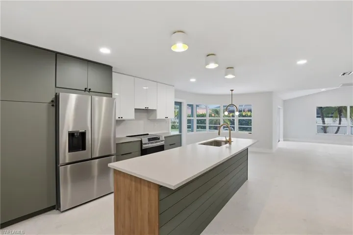 Kitchen featuring an expansive island with a light-toned countertop and wood-finish accent paneling