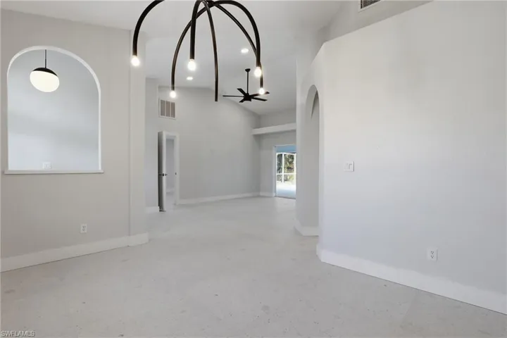 Spacious interior featuring high vaulted ceilings, light-toned flooring, and contemporary overhead lighting fixtures