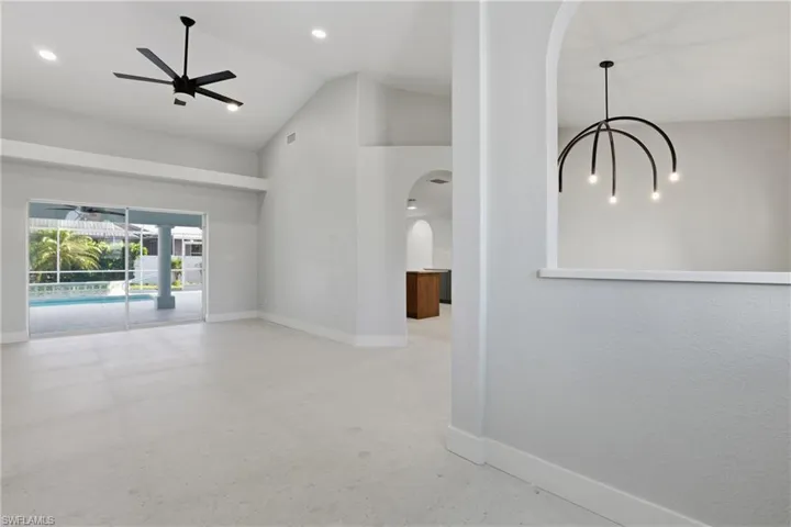 Expansive living area featuring vaulted ceilings with a black ceiling fan, recessed lighting, and light-colored flooring