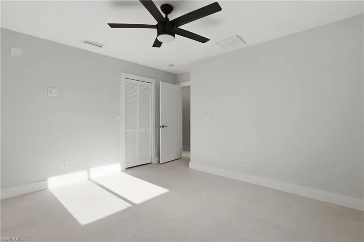 Spacious room featuring light-colored carpeting, white baseboards, and neutral wall tones