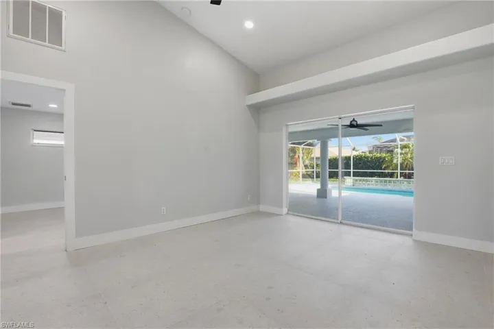 Spacious room featuring vaulted ceilings, light gray wall paint, and light-toned flooring