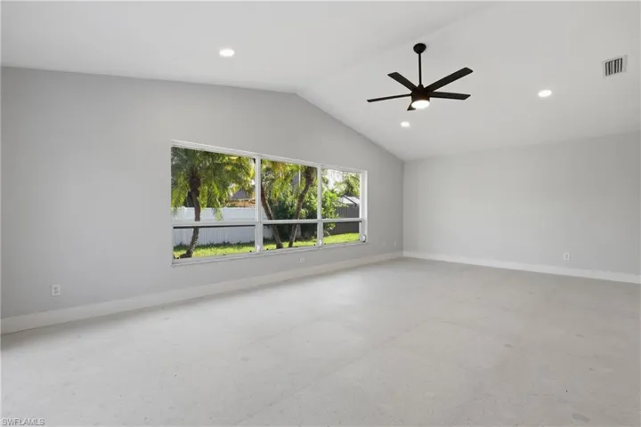 Spacious room featuring vaulted ceilings, a contemporary ceiling fan, recessed lighting, and large windows