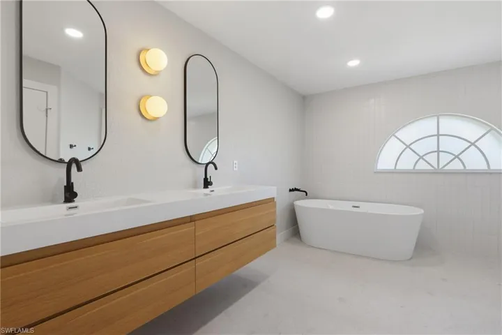 Modern bathroom featuring a freestanding tub and a floating dual vanity