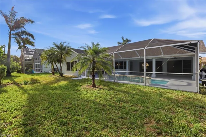Expansive backyard featuring a manicured lawn and mature palm trees