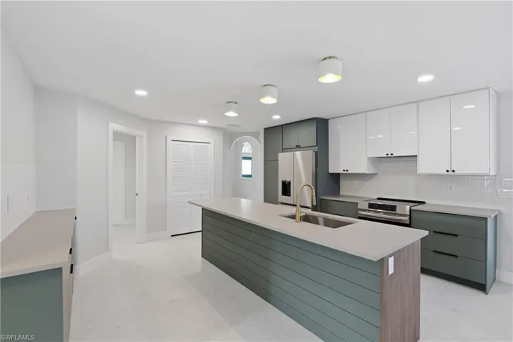Modern kitchen featuring an expansive center island with a wood-finish accent panel and integrated sink