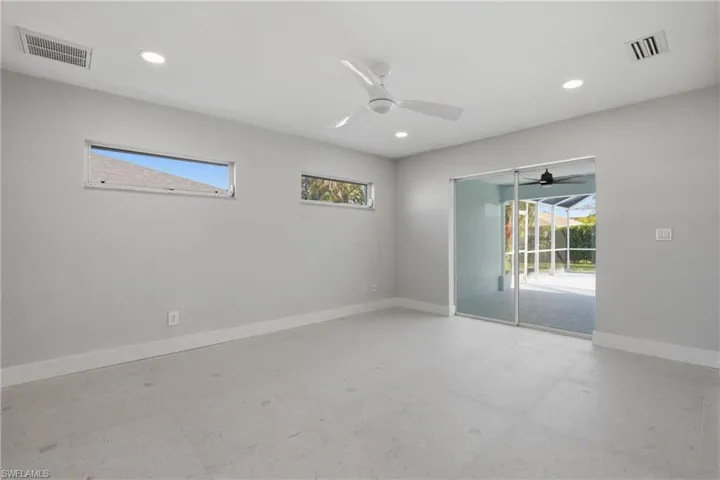 Spacious interior featuring light gray walls, large format tile flooring, and a modern ceiling fan
