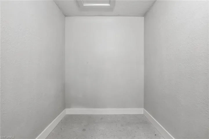Neutral-toned walls with contrasting white baseboards and a concrete floor