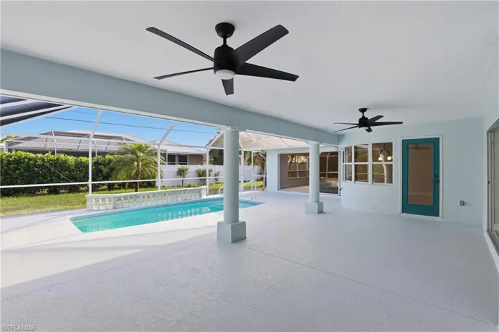 Screened patio featuring a swimming pool, multiple ceiling fans, and a turquoise door