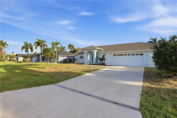 Contemporary exterior with an arched entryway, mature palm trees, a concrete driveway, and an attached two-car garage