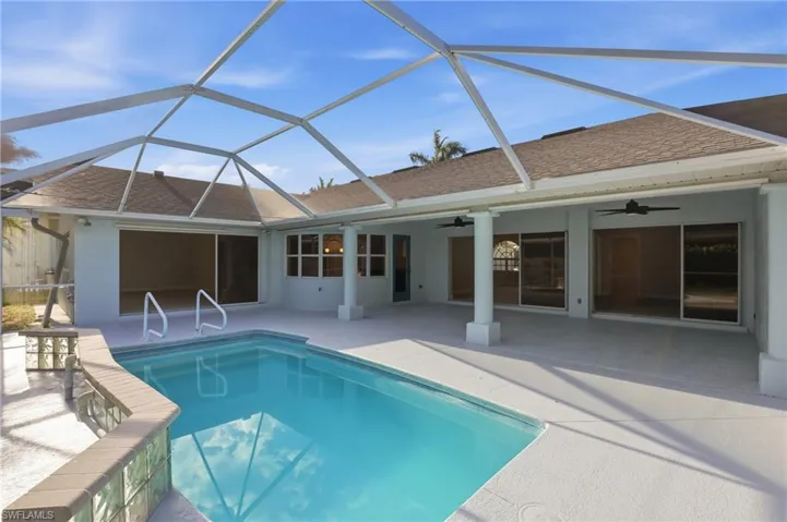 Screened pool enclosure featuring a rectangular pool with integrated steps and handrails