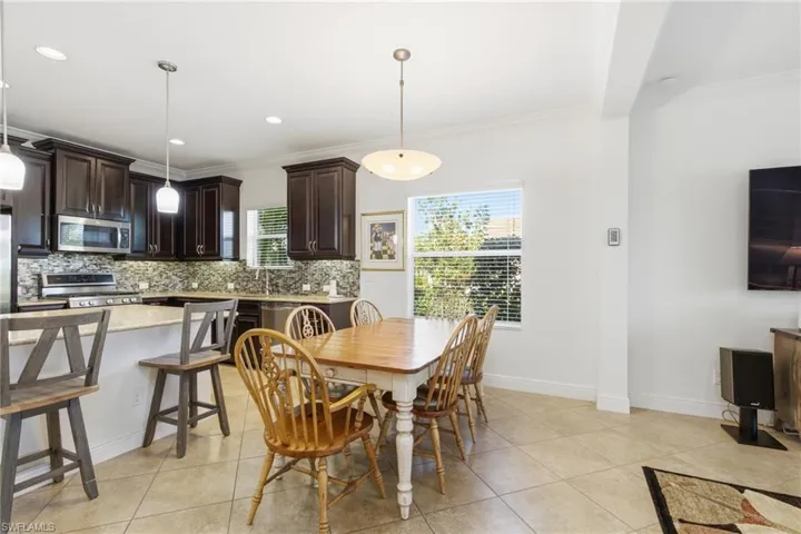 Dining area with light tile patterned flooring, ornamental molding, and recessed lighting