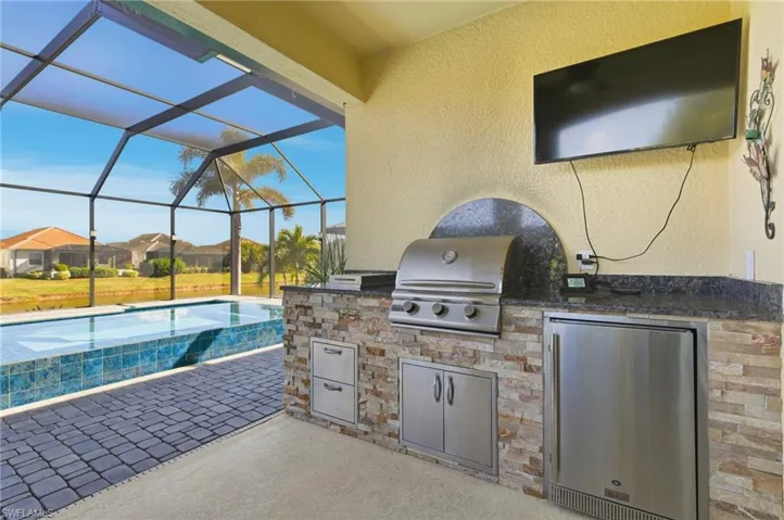 View of patio / terrace with an outdoor pool, a sunroom, a lanai, and exterior kitchen