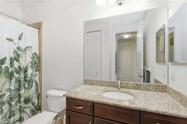 Full bath featuring ornamental molding, a shower with shower curtain, vanity, and a closet