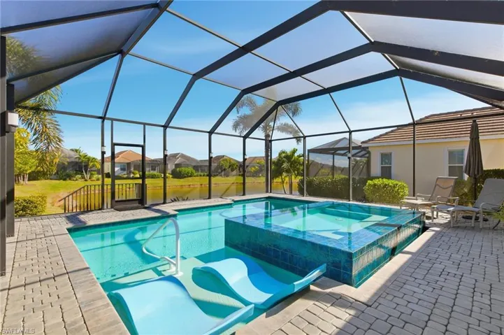 View of pool with a pool with connected hot tub, a lanai, a patio, a sunroom, and a residential view