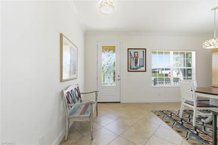 Entryway featuring light tile patterned floors and ornamental molding