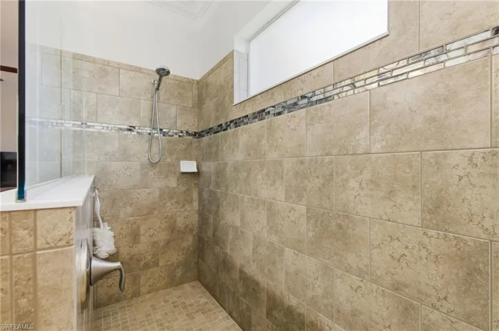 Bathroom with tiled shower and ornamental molding