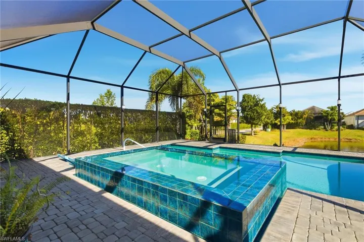 View of swimming pool featuring a pool with connected hot tub, a sunroom, and a lanai