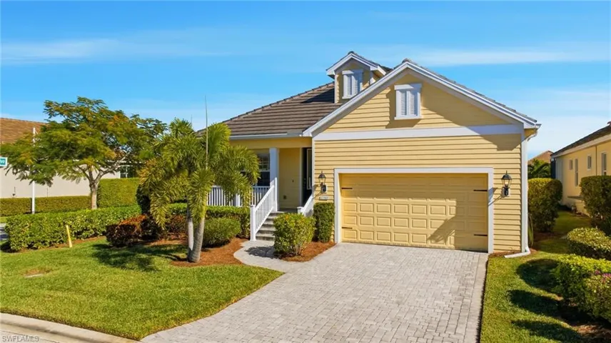 View of front facade featuring a front yard, decorative driveway, and an attached garage