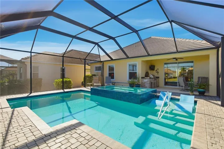View of pool with a sunroom, glass enclosure, a pool with connected hot tub, and a patio