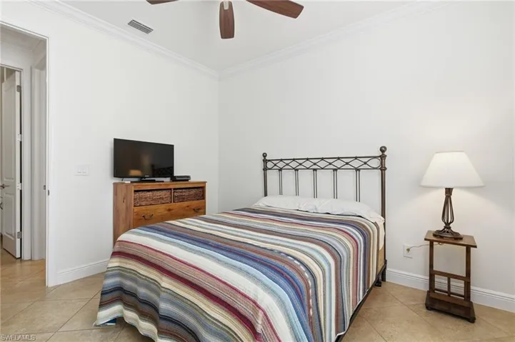 Bedroom with crown molding, light tile patterned floors, and a ceiling fan