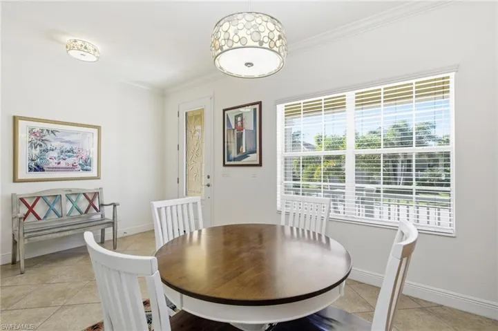Dining area with light tile patterned flooring and crown molding