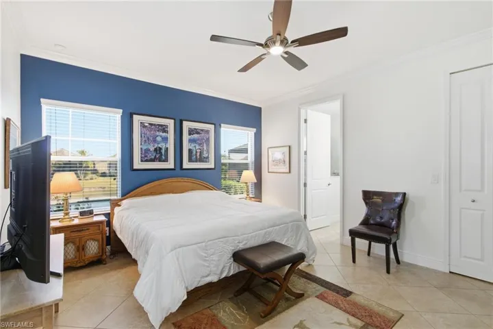 Bedroom featuring light tile patterned flooring, ornamental molding, multiple windows, and ceiling fan