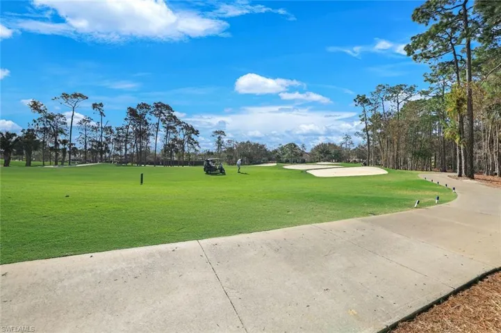 View of property's community featuring view of golf course and concrete driveway