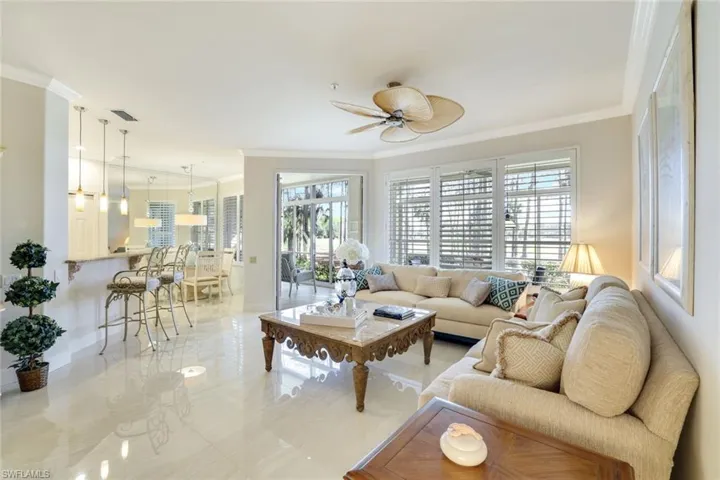 Living room featuring ornamental molding, ceiling fan, and healthy amount of natural light