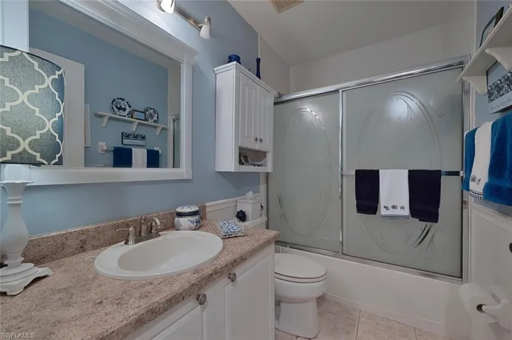 Bathroom with vanity, enclosed tub / shower combo, and tile patterned flooring