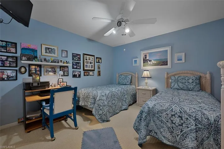 Carpeted bedroom with ceiling fan and a desk